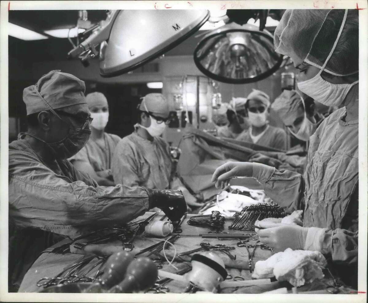 A surgical team led by Dr. Michael DeBakey, left, implants an artificial heart valve at Methodist Hospital in this file photo.