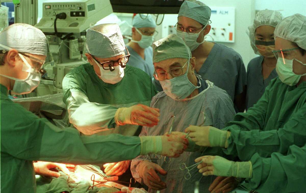 In this 2000 file photo, (LtoR) Dr. Javier Lafuentes, Dr. George Noon, Dr. David A. Joly, Dr. Janice K. Chow MD, and Flo Bell, ORT, work around Dr. Michael E. DeBakey (center), and Dr. Zbignew Wojciechowski (center back). Dr. Debakey had recently completed his 50th year at Baylor College of Medicine. >>> See more historic photos from the Texas Medical Center through the years...