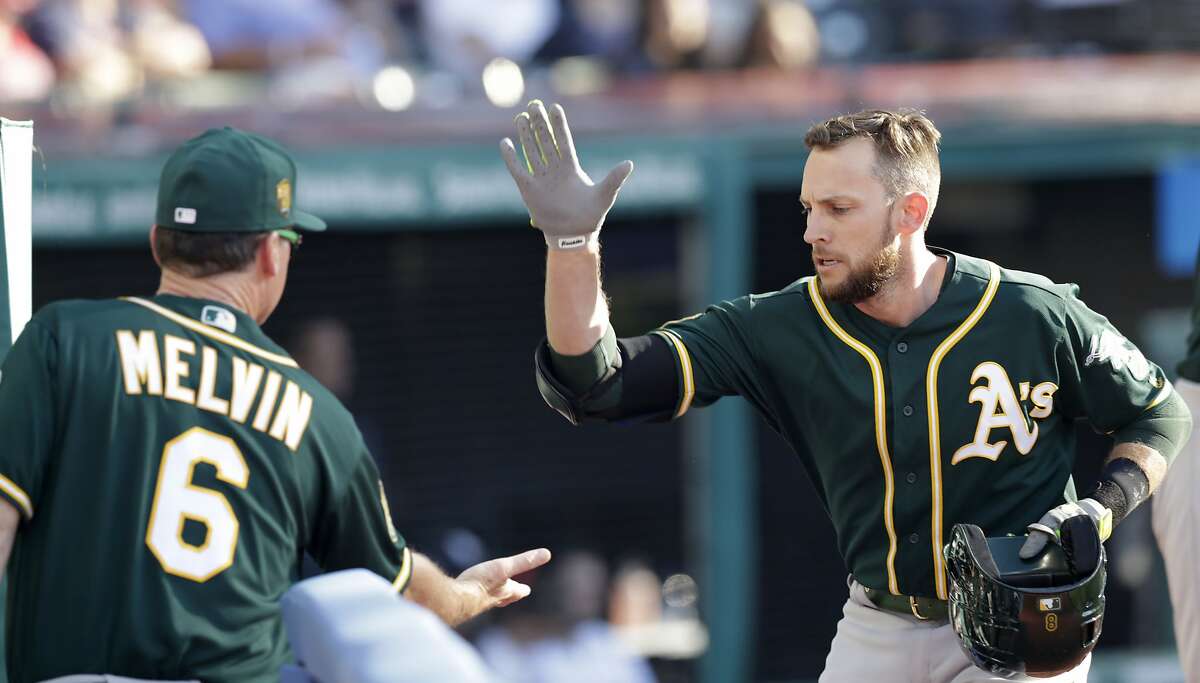 Oakland Athletics' Mark Canha is greeted by Matt Williams as Canha