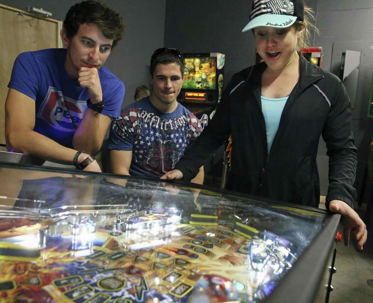 Sabrina Fuller watches her pinball game at What's Brewing? coffeehouse as James Vickers (left) and Brandon Fuller look on. What’s Brewing? has more than 20 pinball machines, and is one of those rare old-school arcades in San Antonio.