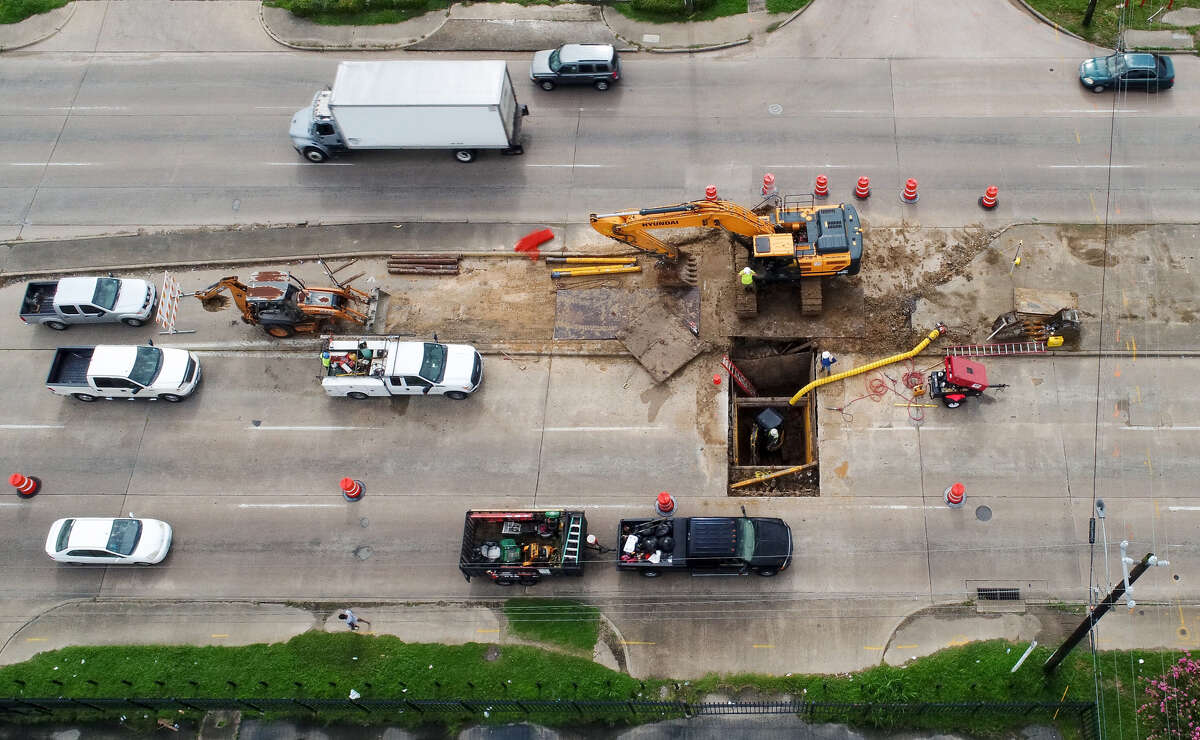 Construction workers repair a sinkhole on South Post Oak Road near Gasmer Drive Monday, July 9, 2018, in Houston.