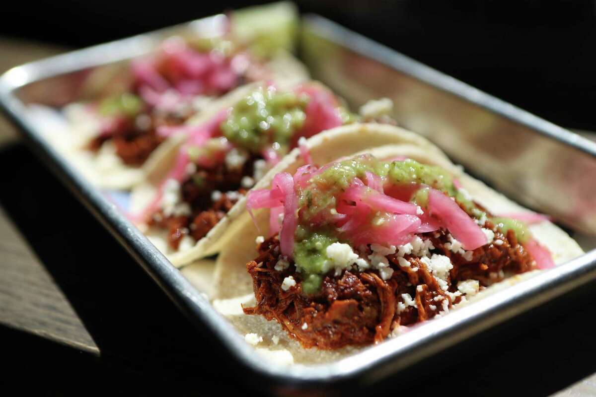 The finished cochinita pibil tacos, topped with pickled onions and habanero salsa at Goodnight Charlie’s.