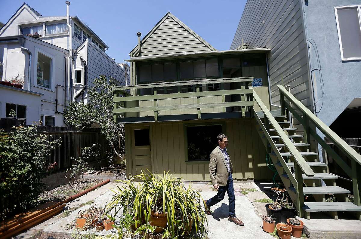 George Limperis, a realtor with Paragon Real Estate Group, walks in the backyard of a property in the Noe Valley neighborhood in San Francisco, Wednesday, July 30, 2014. In the souped-up world of San Francisco real estate, where the median selling price for homes and condominiums hit seven figures for the first time last month, the cool million that would fetch a mansion on a few acres elsewhere will now barely cover the cost of an 800-square foot starter home that needs work and may or may not include private parking. (AP Photo/Jeff Chiu)