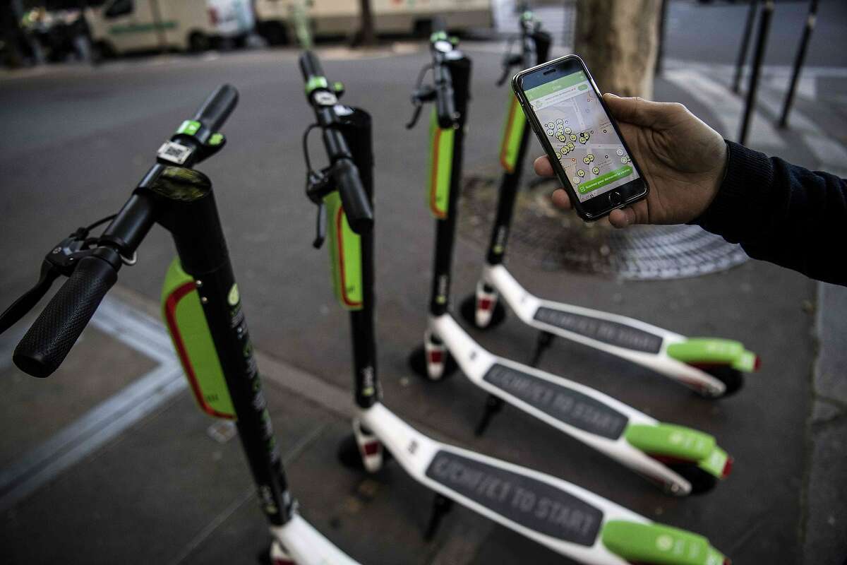 A man shows the mobile application allowing to check the availability of electric scooters of the US company Lime on the day of their launch in Paris on June 22, 2018. / AFP PHOTO / Christophe ARCHAMBAULTCHRISTOPHE ARCHAMBAULT/AFP/Getty Images