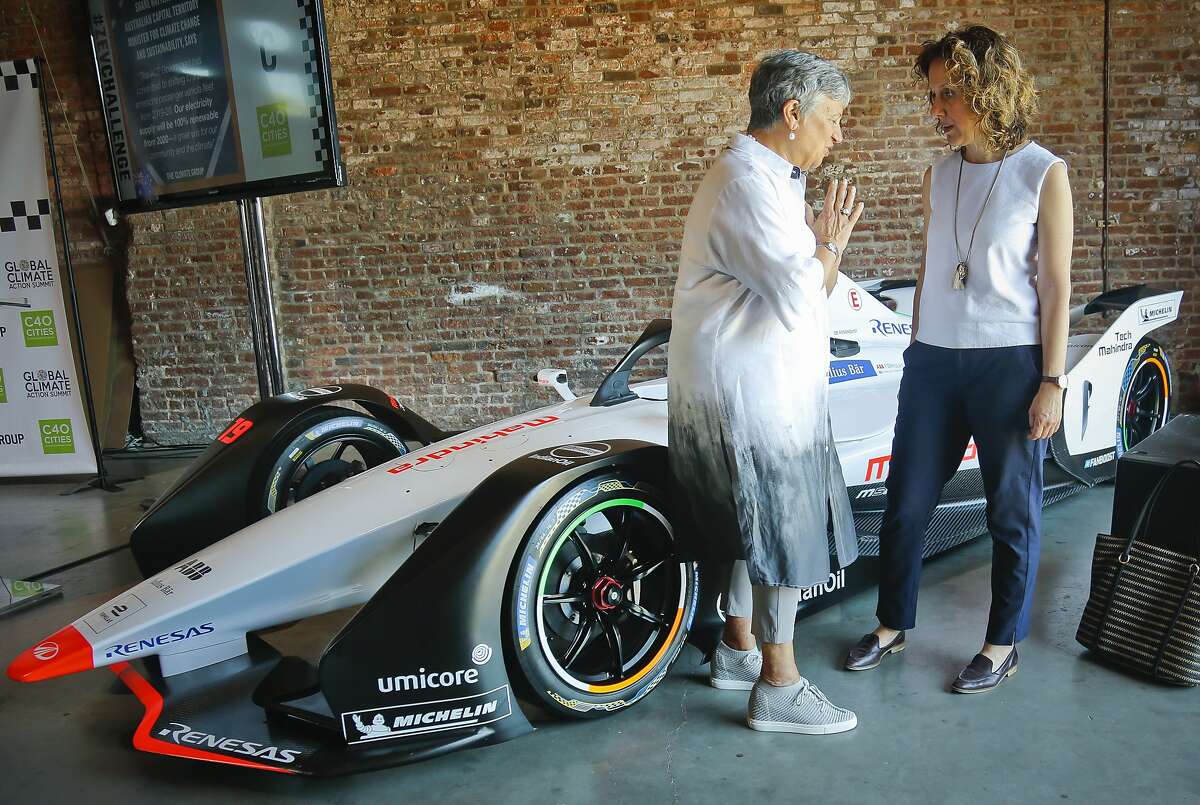 Helen Clarkson, right, CEO of The Climate Group, and Mary Dolores Nichols, left, Chairwoman of the California Air Resources Board, talks as they stand next to a Generation 2 electric Formula-E racing car, as they confer following a climate group panel discussion, Tuesday July 10, 2018, in New York. Clarkson announced a new initiative called Zero Emission Vehicle (ZEV) Challenge, that will see states, regions, cities and international business use their purchasing and policy influence to massively accelerate the adoption of electric vehicles around the world. The Formula E season finale auto race is Sunday in the Red Hook neighborhood in the borough of Brooklyn. (AP Photo/Bebeto Matthews)