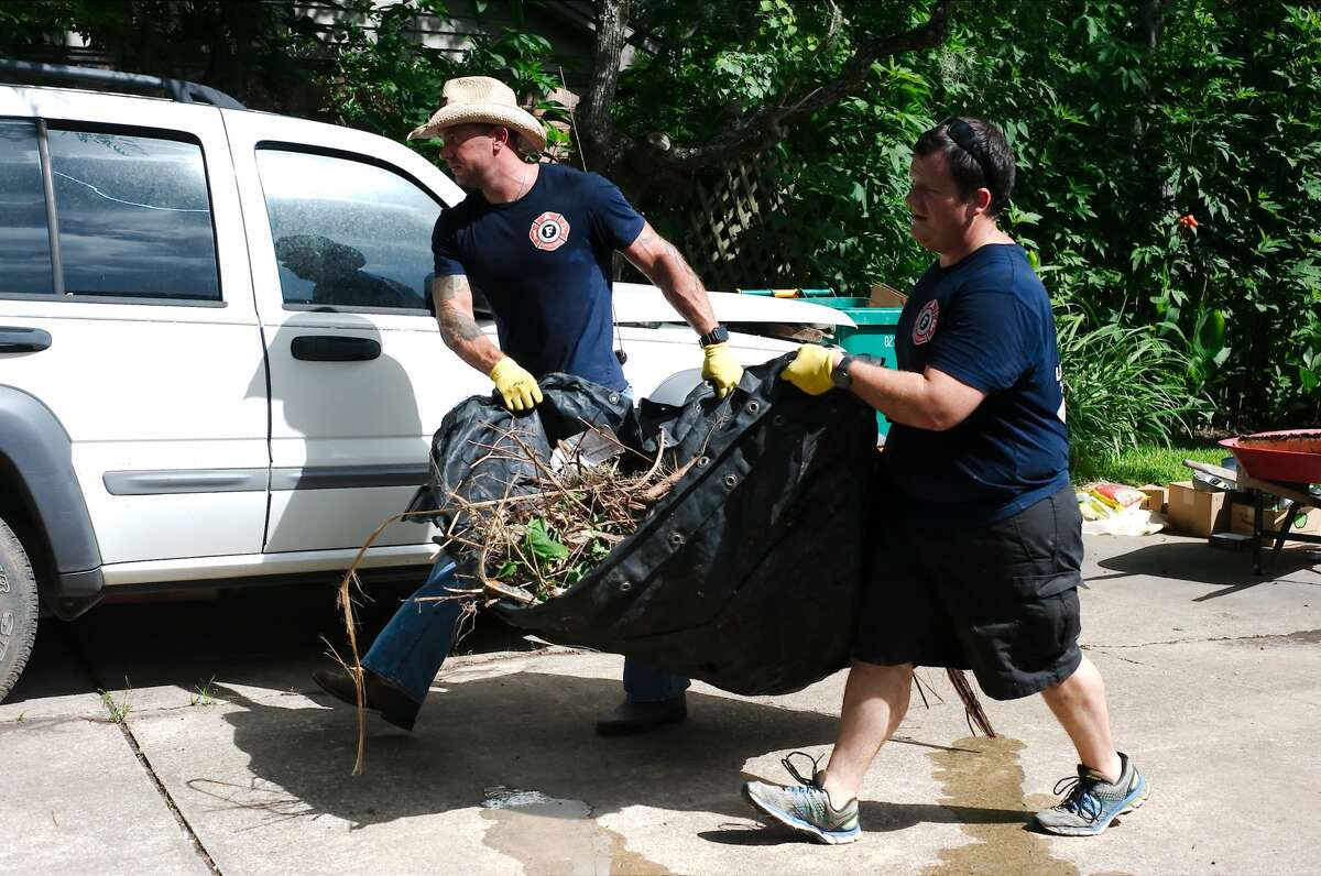 Pearland firefighters Jason Pecknold and Joshua Hendrix carry debris as the members of the Pearland Professional Firefighters Association volunteered Tuesday, Jul. 10 to assist Pearland resident Rosalea Nall with the cleanup of her home damaged during Hurricane Harvey.