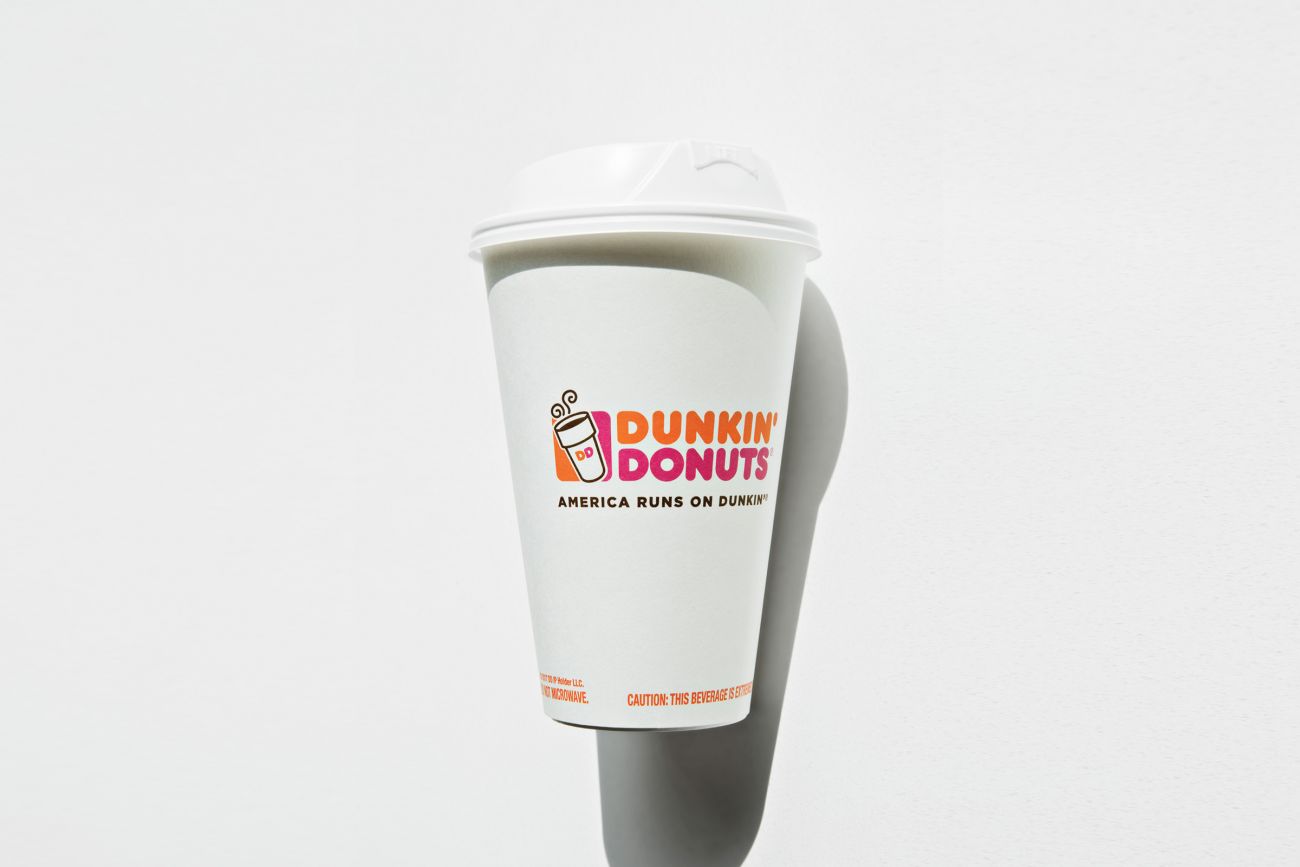 A large white nonrecyclable to-go drink cup with a plastic lid and straw on  a