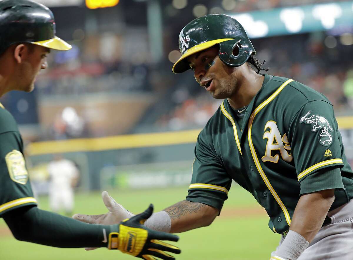 Oakland Athletics' Khris Davis, right, is congratulated by Chad Pinder after scoring during the first inning of a baseball game against the Houston Astros on Wednesday, July 11, 2018, in Houston.