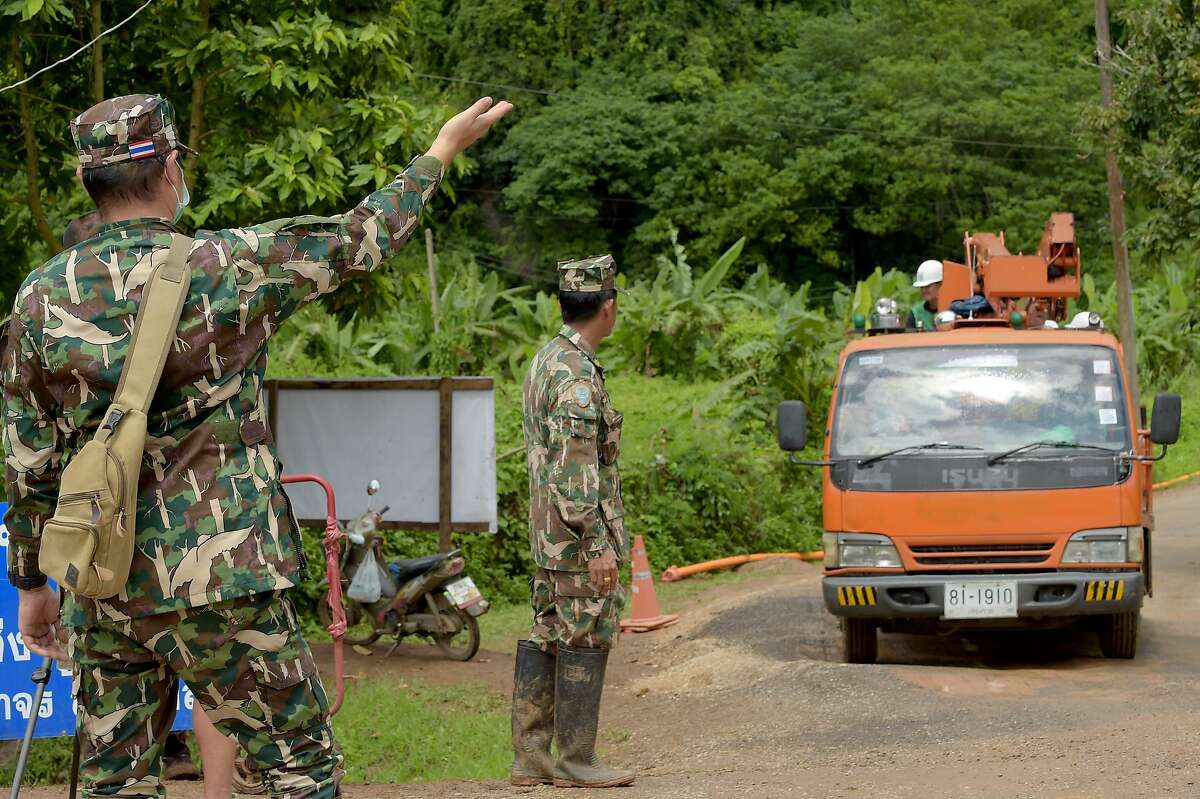 7月12日，泰国清莱省美赛区坤南南侬侬森林公园，一辆卡车驶离Tham Luang洞穴区域，士兵们(左)站在路边。两天后，被困洞穴的最后一名男孩和教练获救。7月12日，救援人员成功拆除了被困洞穴两周的12名足球运动员和他们的教练的现场，这是泰国史无前例的规模，已经引起了电影的兴趣。/法新社图片/唐·钦·索蒂/法新社/盖蒂图片社
