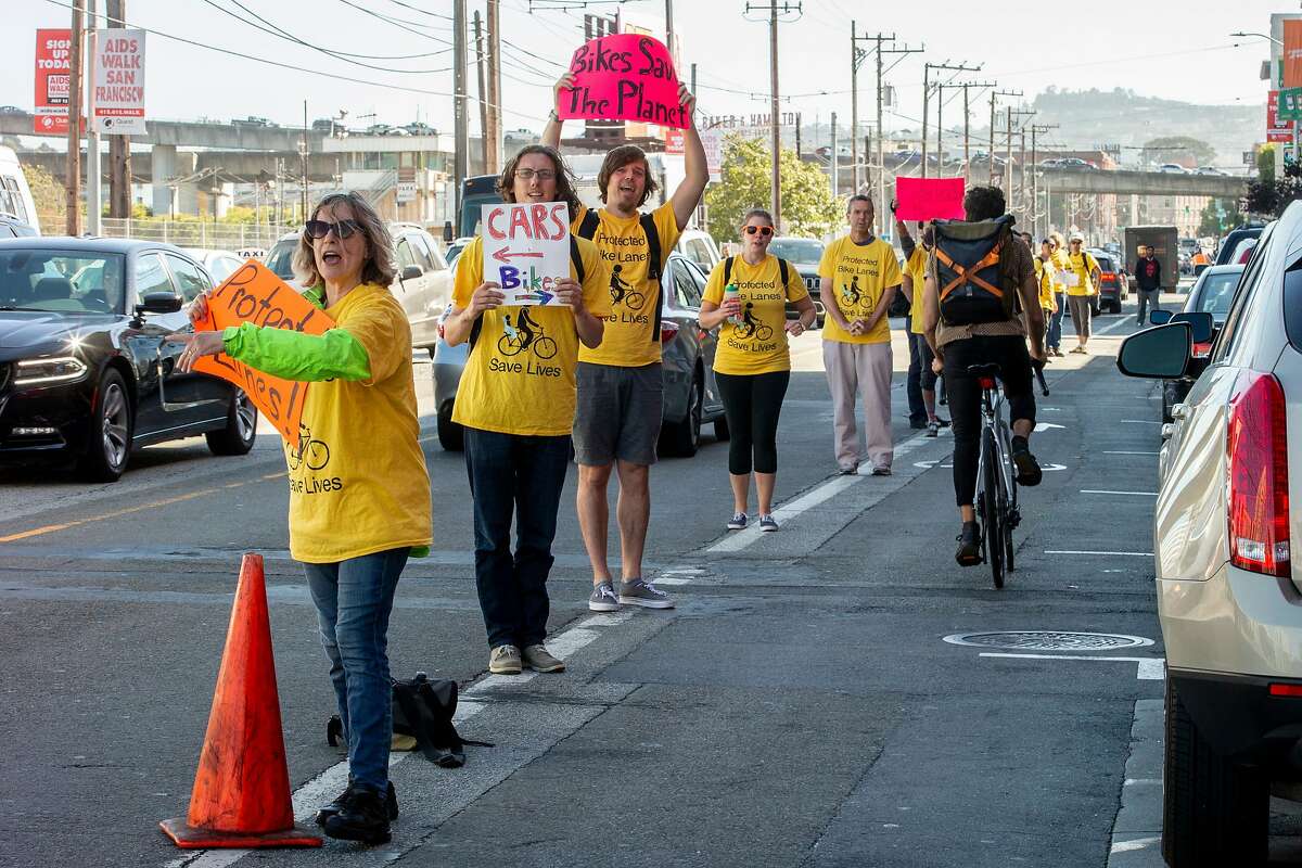 Activists of the People Protected Bike Lane group form a human barrier to separate the car lane from the bike lane, Tuesday, July 10, 2018, in San Francisco, Calif. The demonstration was along Townsend Street between 4th and 5th streets.