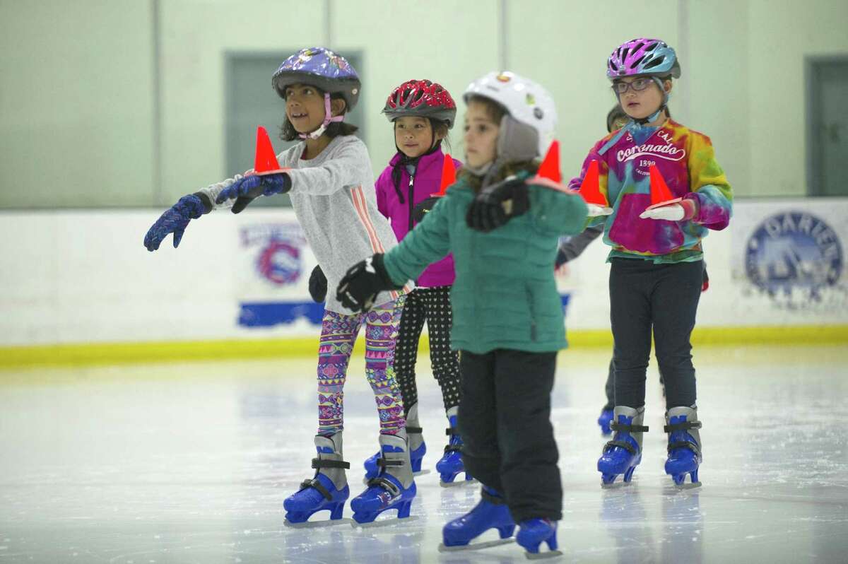 From left, Stamford residents Alysia Patrick-D’Silva, Dylan Manzano, Catherine Tripolitsiotis and Rebecca Notter skate while balancing a cone on their wrist during the youth summer camp at Stamford Twin Rinks on Thursday.
