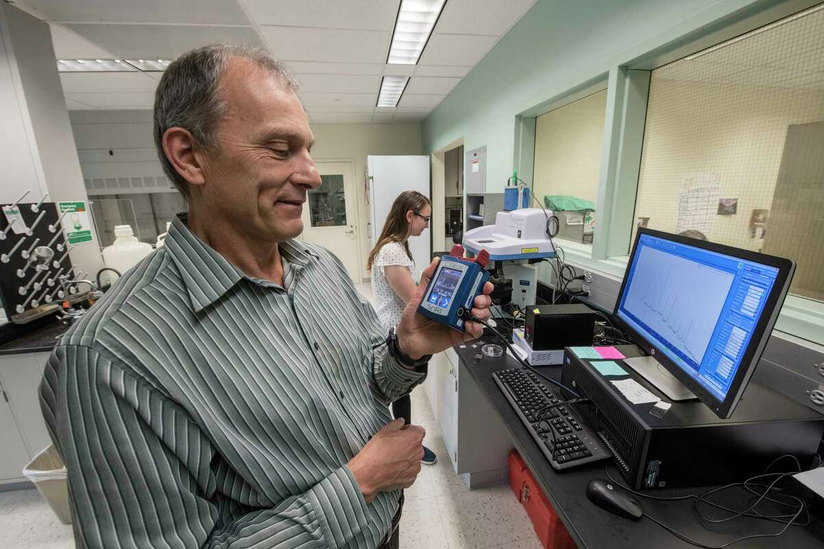 Dr. Igor Lednev is surrounded by devices used in the analysis of blood samples including a hand held device that he is using much like the big devices in his lab at the University at Albany Friday July 13, 2018 in Albany, N.Y. (Skip Dickstein/Times Union)