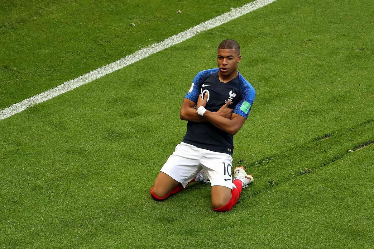  Kylian Mbappe is kneeling on the field with his arms crossed across his chest after scoring a goal for Paris Saint-Germain.