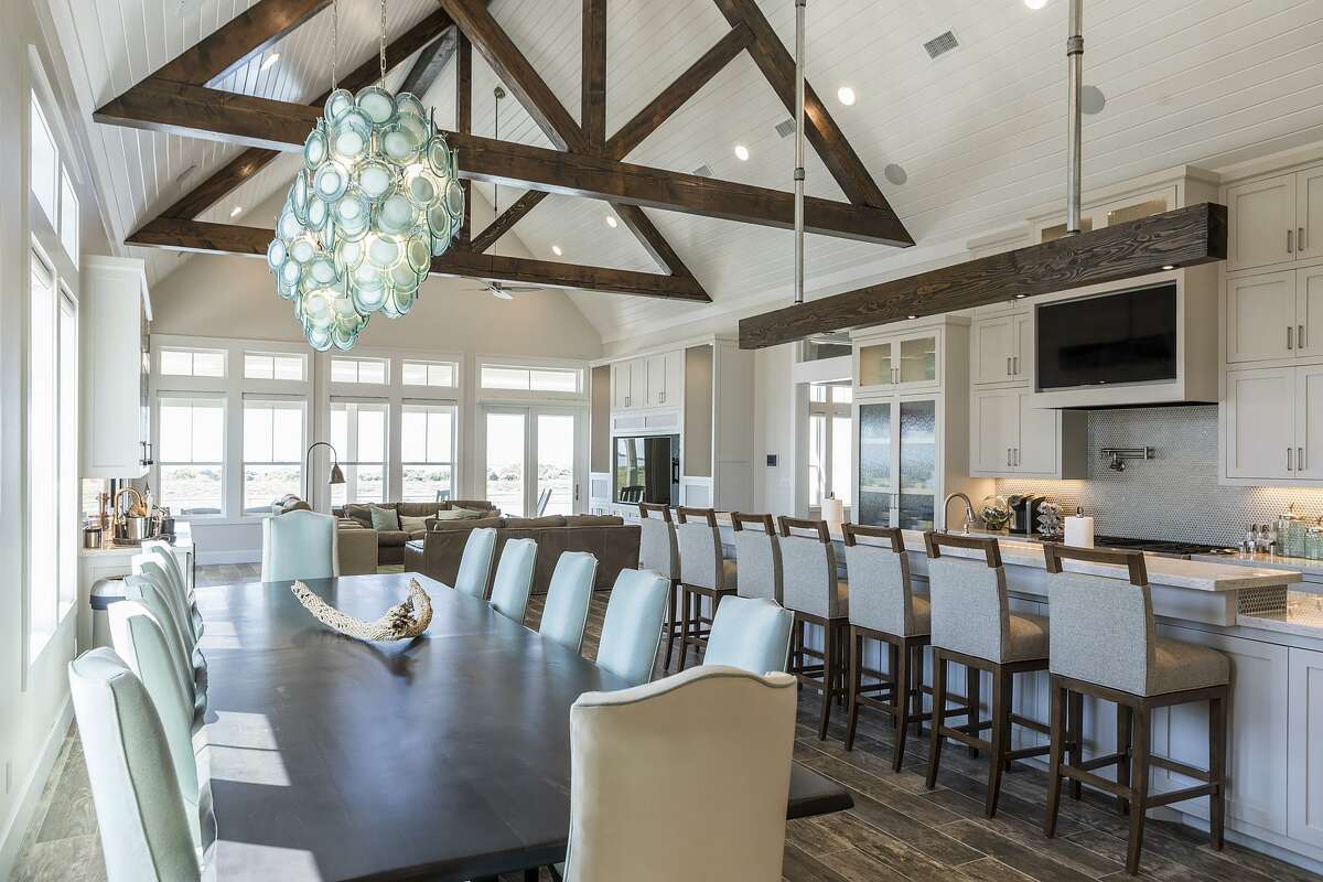 A large light fixture in seaglass green hangs over the dining table, which seats 12. The island seats seven more.