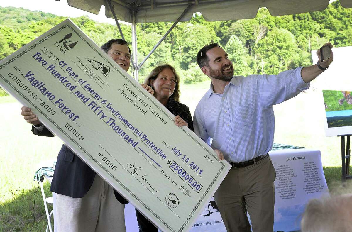 Robert Klee, DEEP commissioner, right takes a selfie with Tim Abbott, left and Lynn Werner with the Housatonic Valley Association and a check for $250, 000, Friday, July 13, 2018 in Kent. The last piece of funding for another Highlands property was completed with a $250,000 anonymous donation.