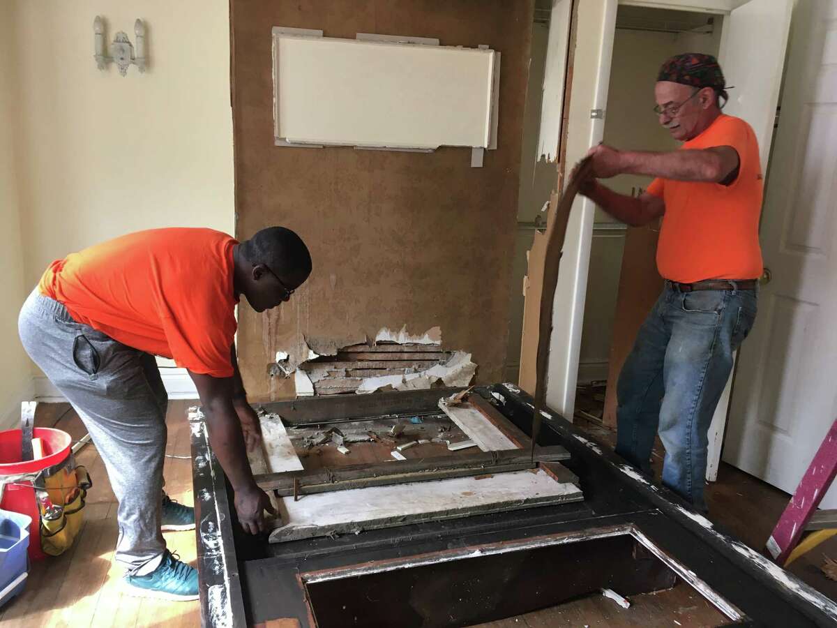 Owusu Anane, left, and Peter Leue, right, work to salvage a mantle at a house at 192 Partridge St. on Saturday, July 14, 2018.