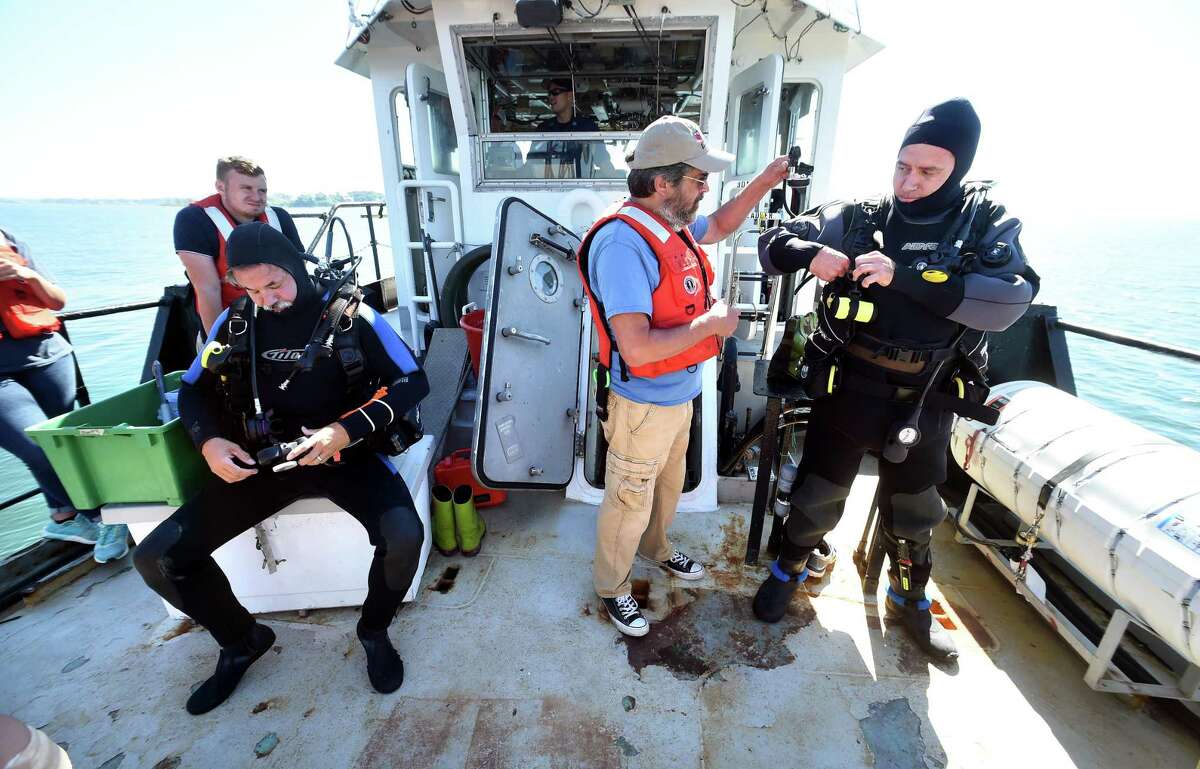 Mark Dixon, left, and Keith Golden, right, prepare to dive into Long Island Sound at the Charles Island reef off the Milford coast to attach GoPro cameras to structures attached to boulders on the the floor of the Sound for a study by NOAA’s Northeast Fisheries Science Center on July 10. At center is diving supervisor Barry Smith.