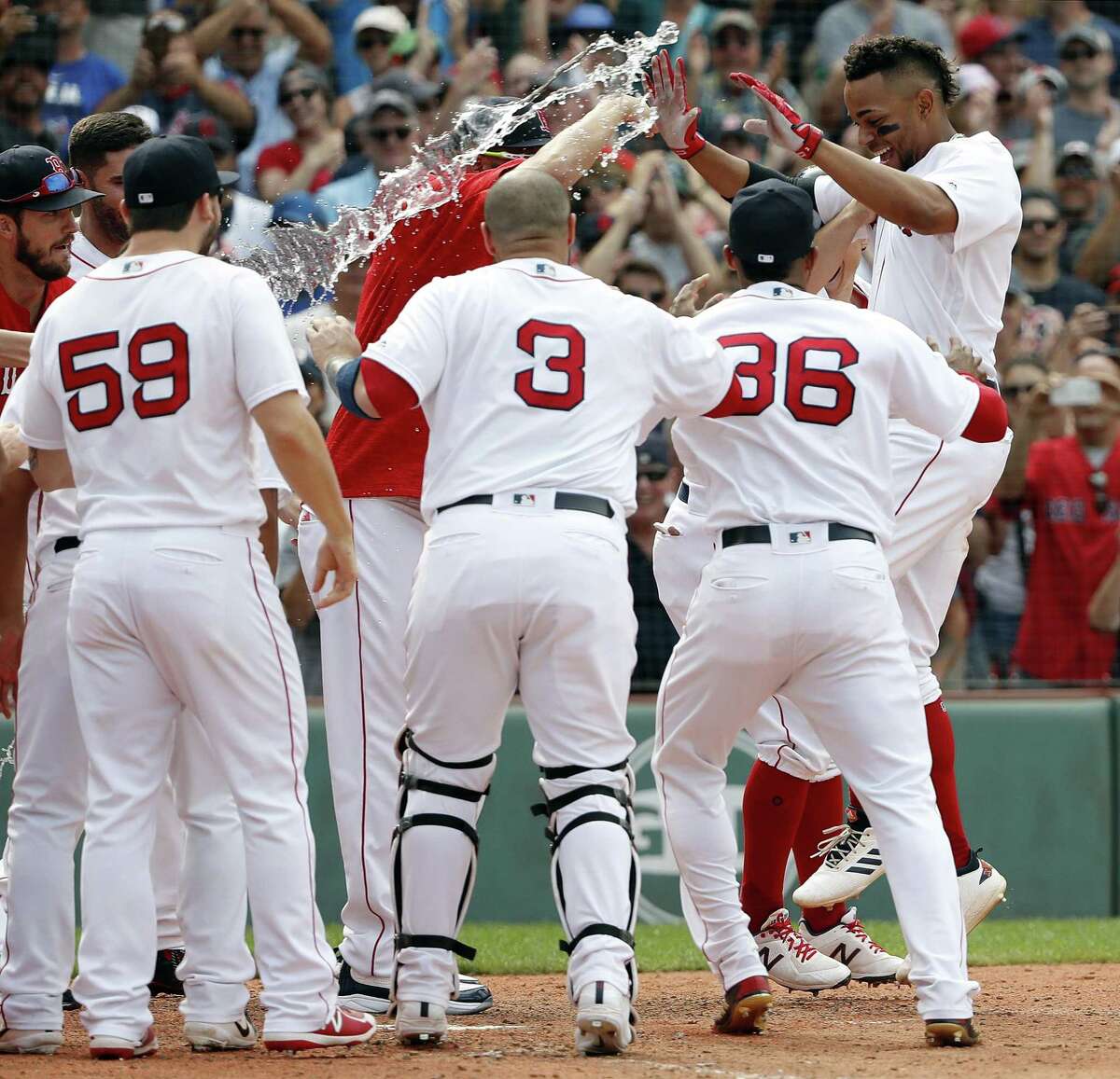 Xander Bogaerts, right, is greeted by teammates at home plate after hitting a grand slam in the 10th inning against the Blue Jays on Saturday.
