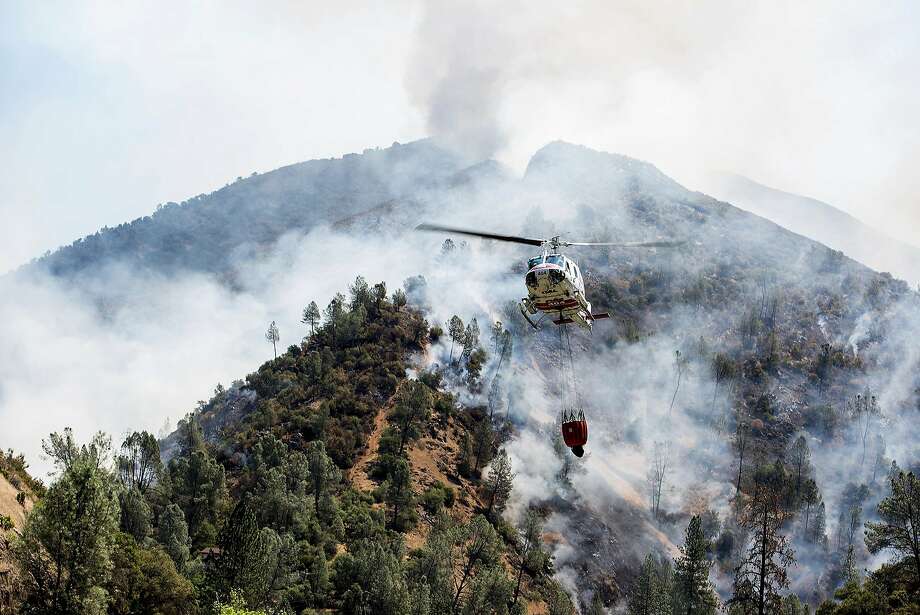   A helicopter recovers the water from the Merced River to fight the Ferguson fire along a steep terrain behind the Redbud Lodge near El Portal, along Route 140 in the county of Mariposa, California, Saturday, July 14, 2018. (Andrew Kuhn / The Merced Sun-Star via AP) Photo: Andrew Kuhn, Associated Press 