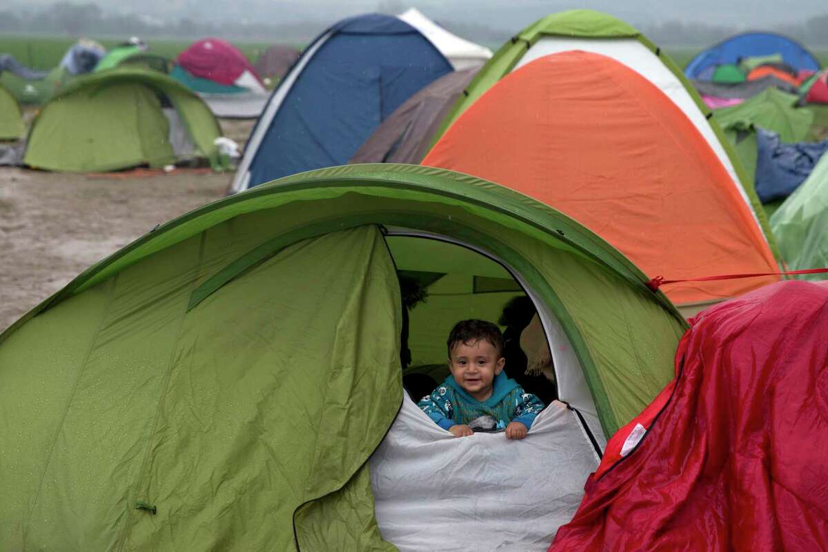 FILE - In this Feb. 24, 2016 file photo, a Syrian children looks out from a tent during rainfall, as refugees wait to be allowed to cross the the Greek-Macedonian border near the northern Greek village of Idomeni. President Donald Trump's recent lament this week that immigration is "changing the culture" of Europe is echoing rising anti-immigrant feelings on both sides of the Atlantic, where Europe and the United States are going through transformative demographic changes that makes some of the white majority uncomfortable. (AP Photo/Petros Giannakouris, file)