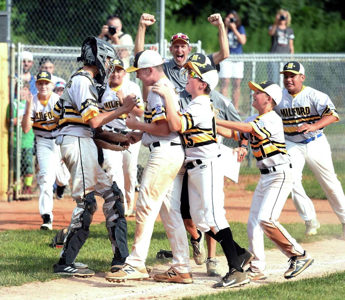 Lou Gehrig players mob relief pitcher Zach Worzel, center, after defeating North Haven’s Max Sinoway squad 3-1 in the District 4 championship game in Milford on Saturday.