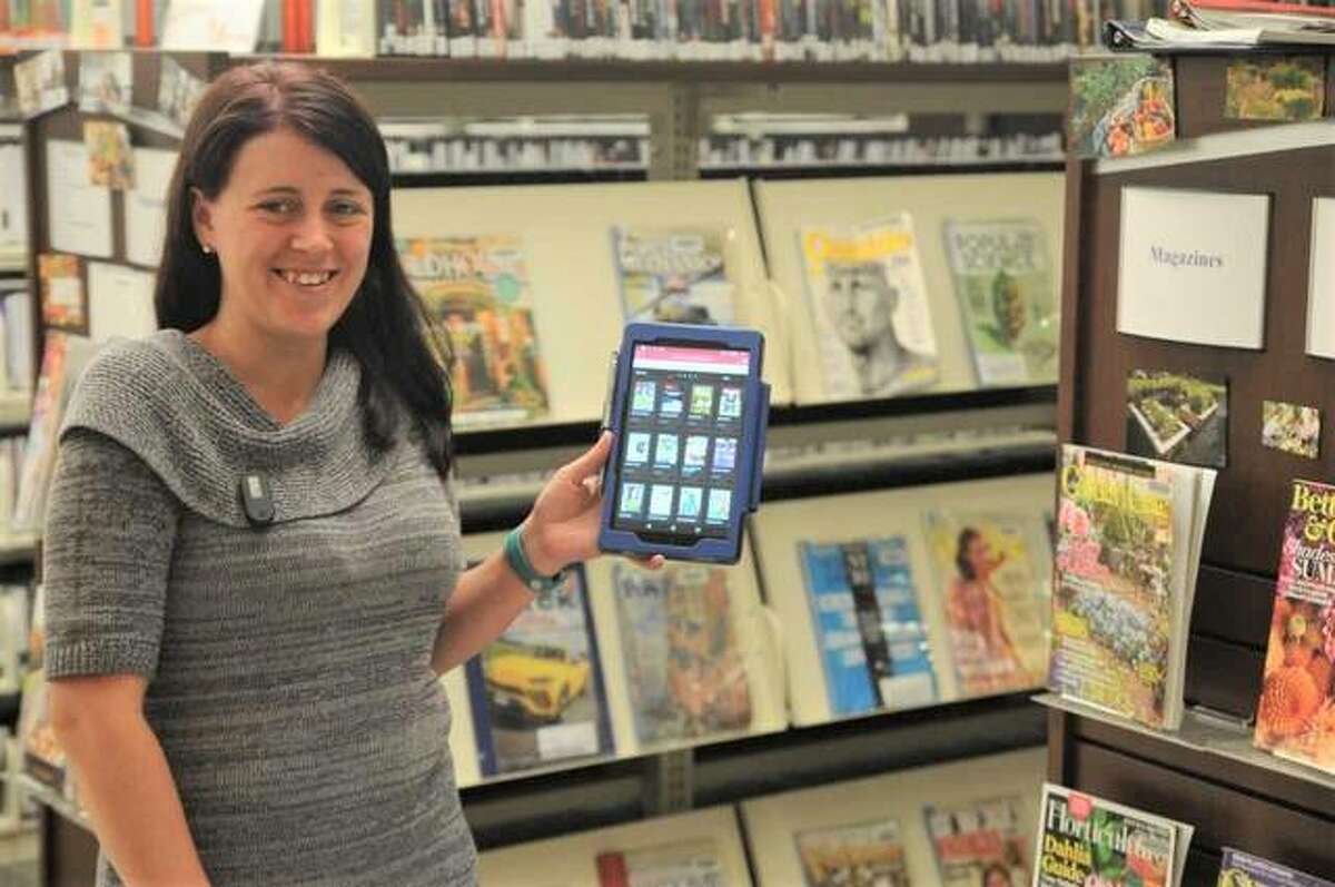Hayner Public Library assistant Amanda Painter demonstrates the library’s new e-magazine service next to the printed magazine section at the library’s Alton Square Mall location.