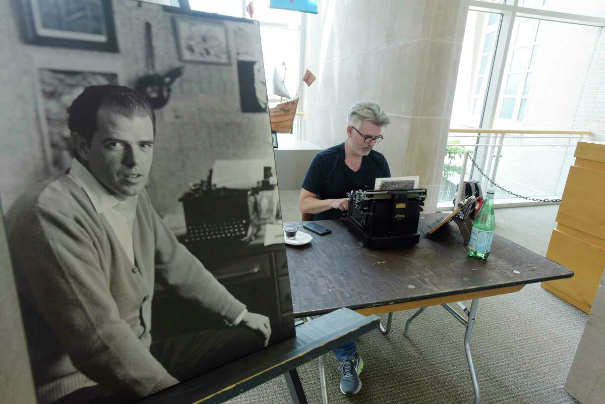 A photo of a young William Kennedy is seen on display as artist Tim Youd retypes "Ironweed" by Kennedy at the Albany Institute of History & Art on Sunday, July 15, 2018, in Albany, N.Y. as part of his 100 Novels Project. For each novel, Youd uses the same make and model typewriter used by the author. He types each novel on a single sheet of paper, which is backed by an additional support sheet. The two-ply paper is loaded through the typewriter repeatedly, until the entire novel has been retyped. Once finished, the two pages are separated and mounted side by side as a framed diptych, recalling two pages of an open book with the words obscured. Youd will be continuing the typing Tuesday Through Saturday. Thursday evening from 6:00pm to 7:45pm there will be a special tasting on the museum grounds of Albany Distilling Company's Ironweed line. (Paul Buckowski/Times Union)