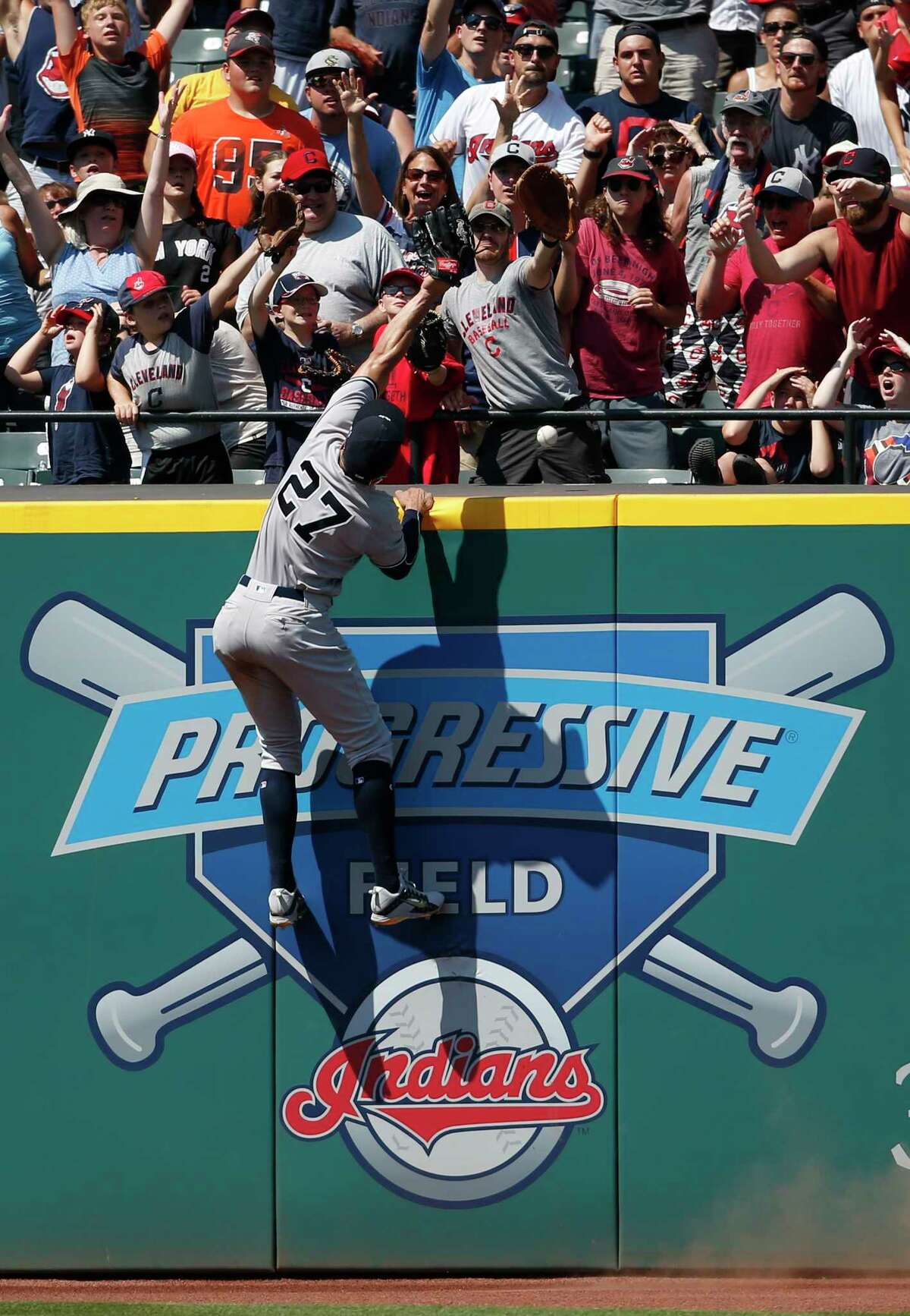 New York Yankees' Giancarlo Stanton (27) attempts to catch a home run by Cleveland Indians' Michael Brantley during the eighth inning of a baseball game, Sunday, July 15, 2018, in Cleveland. (AP Photo/Ron Schwane)