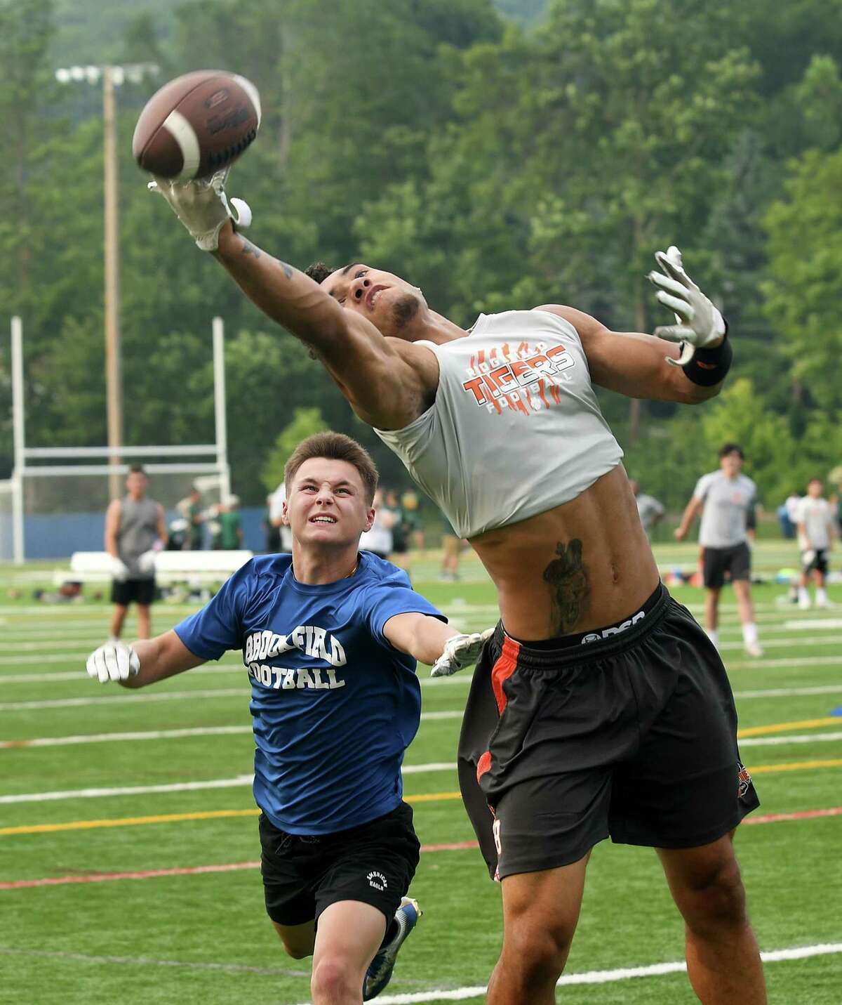 Ridgefield's Jackson Mitchell tries to pull in a pass in front of Brookfield's Joe Bednarik during summer passing league football at Brookfield, July 16, 2018.