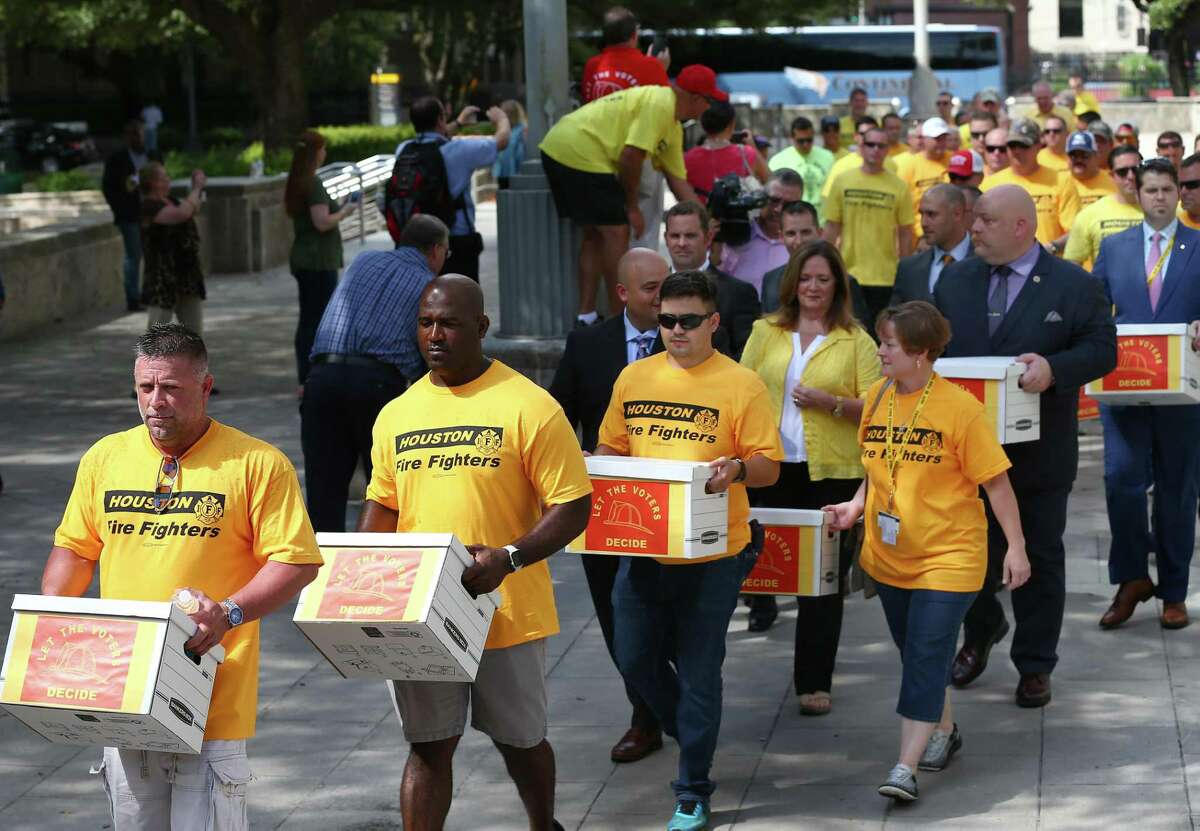 Houston firefighters carry boxes, filled with more than 32,000 signatures to put equal pay on the ballot, over to the City Hall Annex building Monday, July 17, 2017, in Houston. ( Godofredo A. Vasquez / Houston Chronicle )