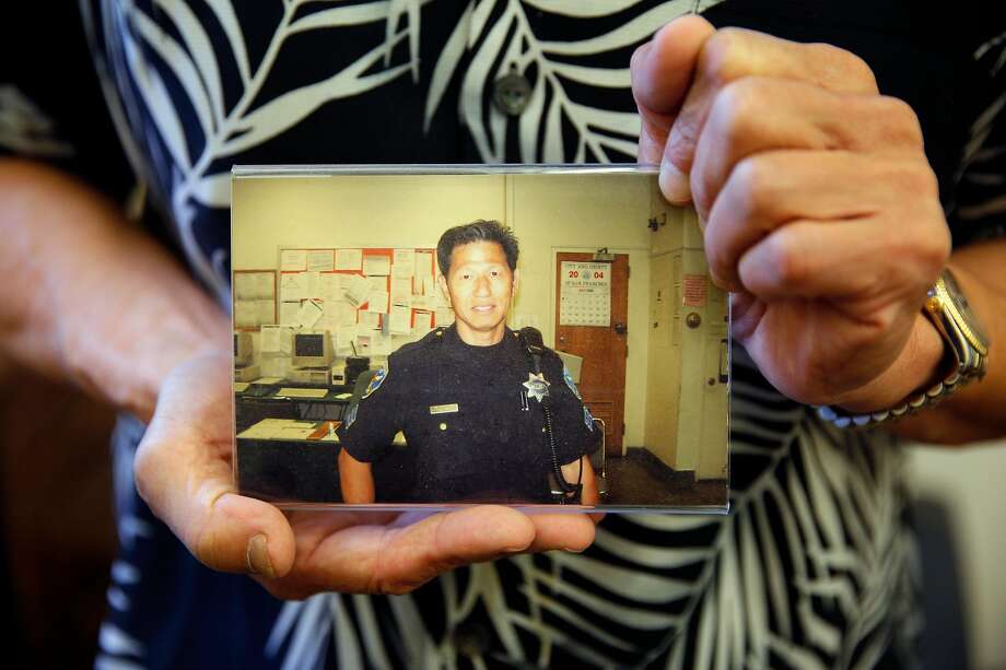 Nelson Lum holds a photo of himself as a San Francisco police officer. Lum, now retired, worked in Building 606 at the former Hunters Point Naval Shipyard, a Superfund cleanup site. Lum and several other officers contracted cancer but are not sure working at Building 606 is linked to the disease. Photo: Santiago Mejia / The Chronicle