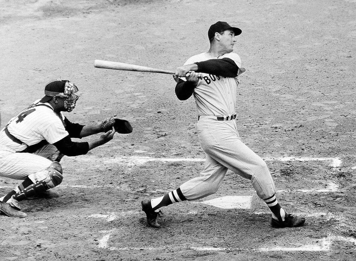 FILE - In this April 18, 1960, file photo, Ted Williams of the Boston Red Sox knocks the ball out of the park for a home run in the second inning against the Washington Senators. The Washington catcher is Earl Battey. A new film explores the life of baseball legend Williams who struggled with his Mexican-American heritage and his volatile relationship with his family and the press. The upcoming PBS "American Masters" documentary on the former Boston Red Sox slugger uses rare footage and family interviews to paint a picture of a complicated figure that hid his past but later spoke out and defended black players. (AP Photo/File)