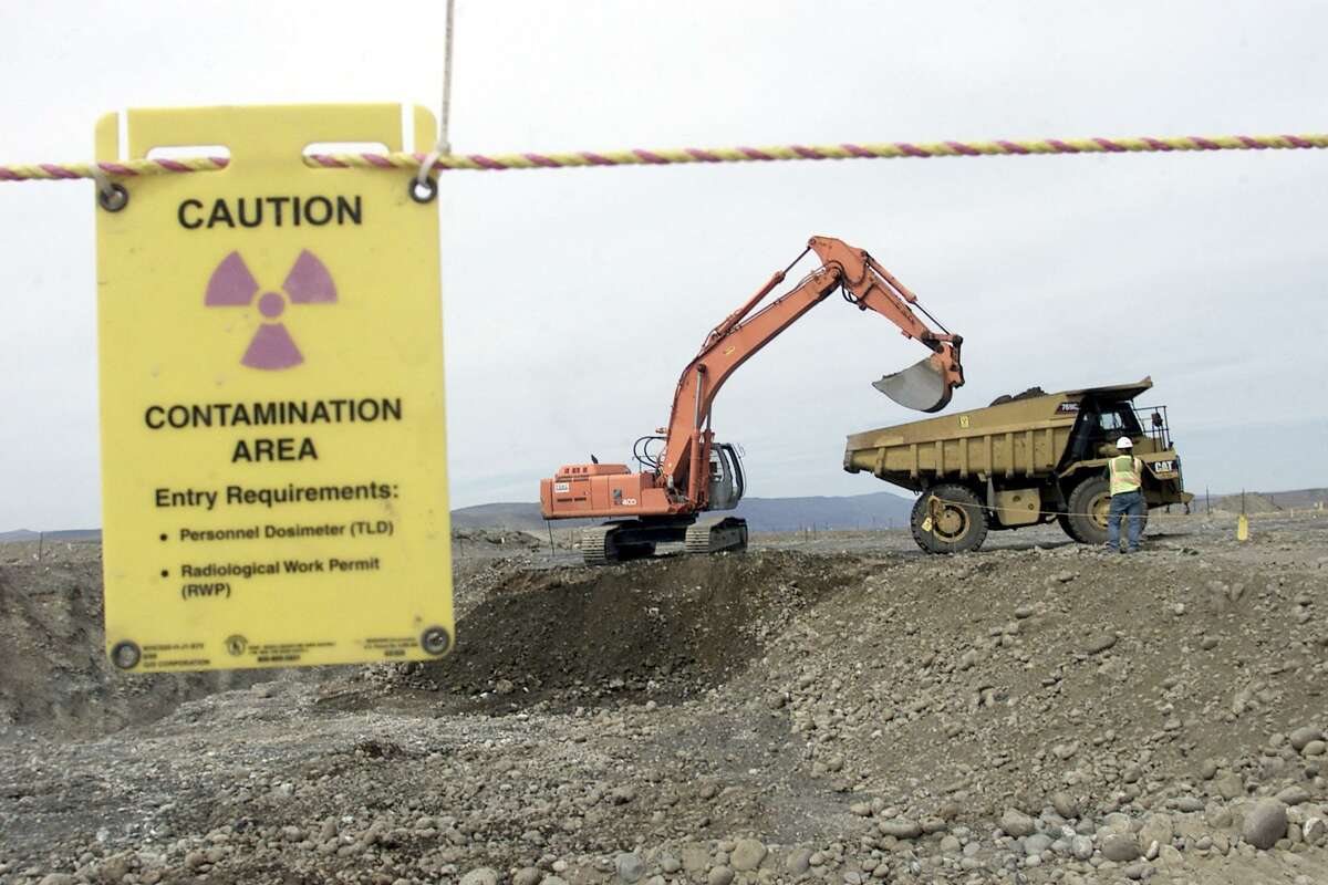 FILE- This May 6, 2004 file photo shows workers as they remove waste in an area near two dormant nuclear reactors on the Hanford nuclear reservation, near Richland, Wash. The world's first full-scale nuclear reactor is one stop on tours of the southeastern Washington state reservation created as part of the Manhattan Project to build the atomic bomb. Now, more than two decades after it stopped producing plutonium, Hanford is the nation's most contaminated nuclear site. (AP Photo/Jackie Johnston, FILE)
