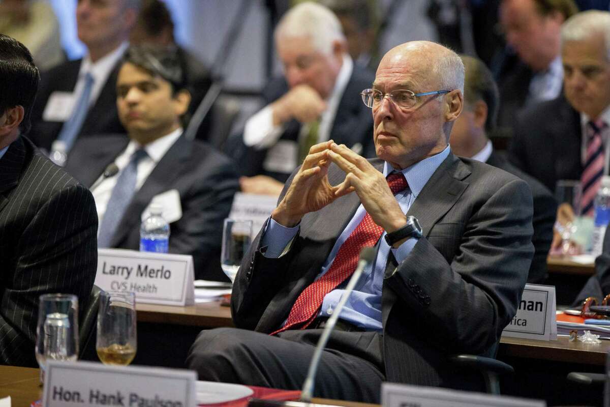 In this Sept. 16, 2015, photo, former Treasury Secretary Henry Paulson listens as President Barack Obama speaks to business leaders at the quarterly meeting of the Business Roundtable in Washington to renew his calls for increased spending in infrastructure, education and scientific research. Three officials including Paulson who played vital roles in combating the 2008 financial crisis say they worry that the painful lessons from the banking systems near-collapse a decade ago may be forgotten.