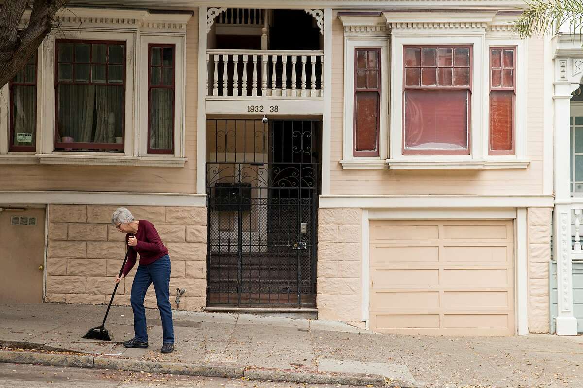 Property owner Noni Richen sweeps the leaves in front of the four-unit rent-controlled apartment she owns in the Western Addition neighborhood of San Francisco, Calif. Thursday, July 19, 2018.