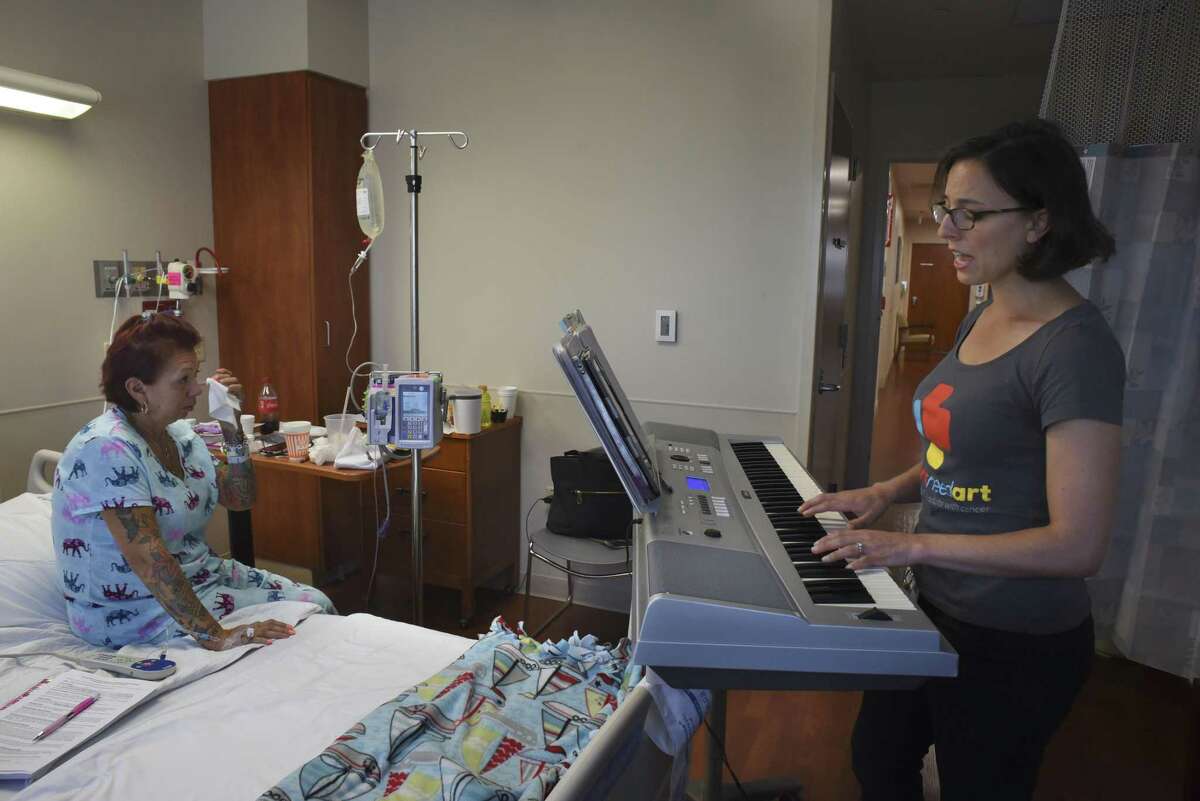 Constanza Roeder, CEO of Hearts Need Art, sings a song called "Oceans" by Hillsong to cancer patient Patricia Gutierrez, who wipes away a tear, at Methodist Hospital.