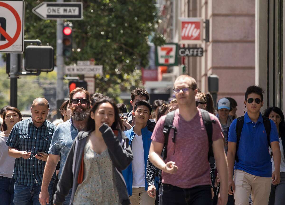 Dozens of San Francisco workers, residents and tourists make their way down Mission Street at New Montgomery in the South of Market district of San Francisco, Calif. Friday, July 20, 2018.