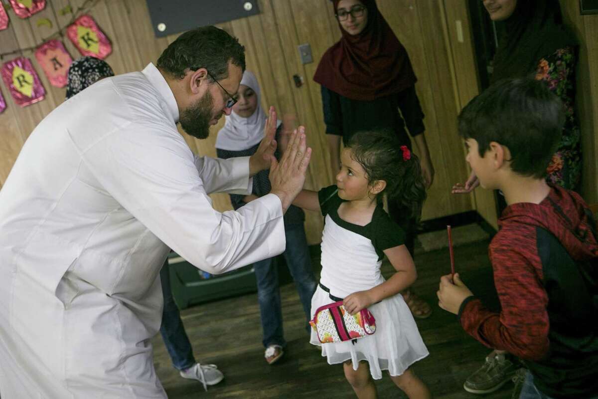 Osama Hassan high-fives Huda Nusayr, 4, for her efforts during the bake sale. The mosque had to be rebuilt following a fire Jan. 28, 2017.