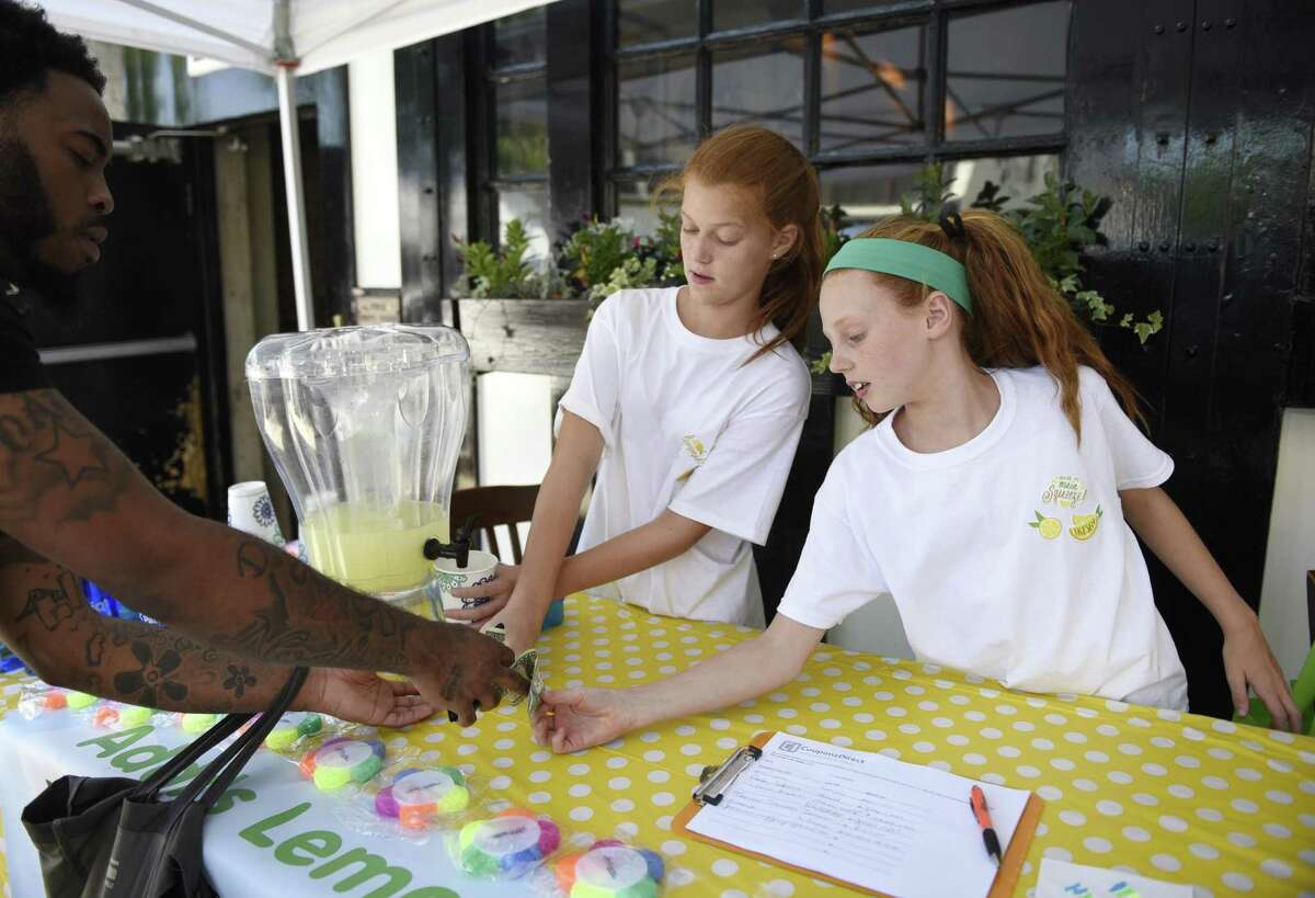 Sam Buck's classmates Devon O'Loughnane, 12, and Addison O'Loughnane sell lemonade to raise money to help Sam, who has Vanishing White Matter Disease, at the 2018 Sidewalk Sale Days in downtown Greenwich, Conn. Thursday, July 12, 2018.