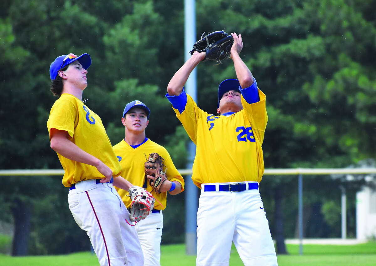 Post 199 pitcher Brandon Hampton makes a catch on the mound with third baseman Cole Hampton, left, and shortstop Tate Wargo, center, watching.