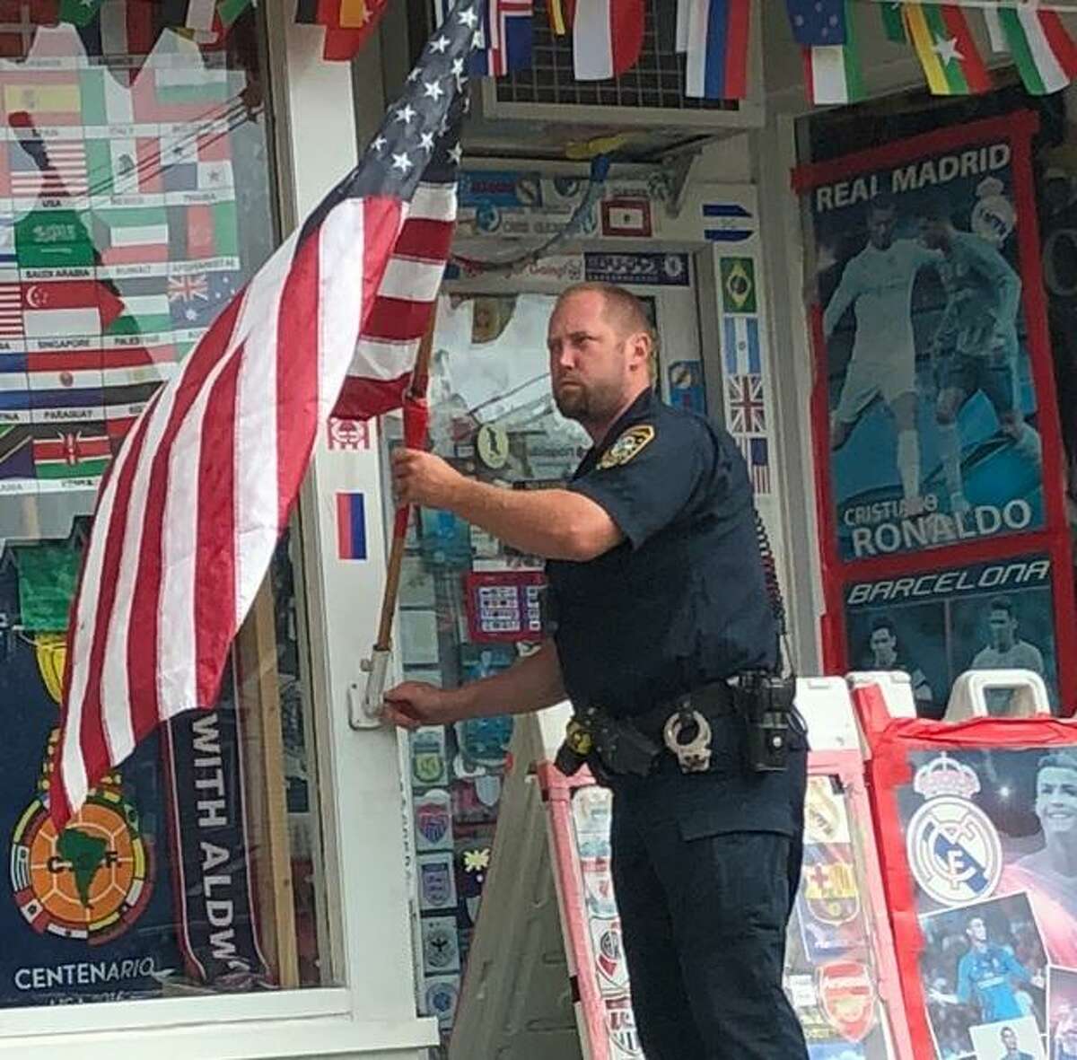 Norwalk Police Officer David Peterson puts an American flag back into the flagpole bracket at the at Soccer Aldwin store at 21 First St. in Norwalk on Sunday, July 22, 2018. The photo was taken by Marc D’Amelio and shared with the Norwalk Police Department.