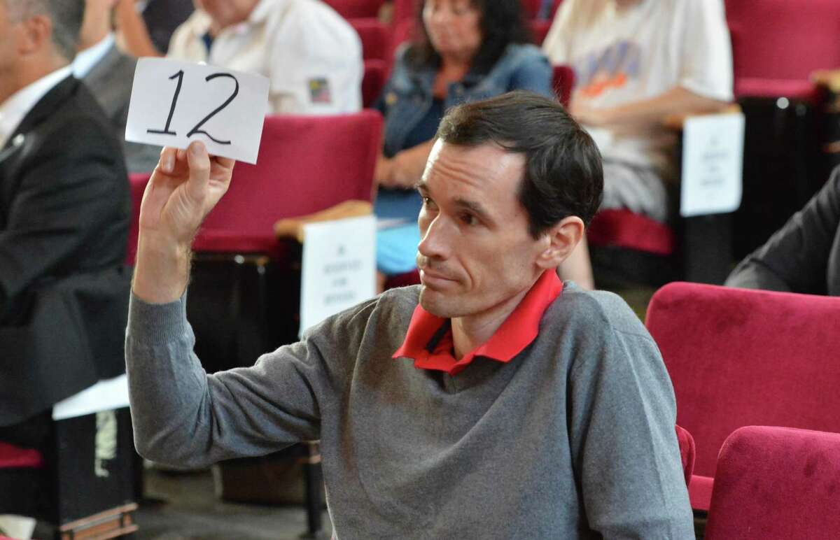 A bidder raises his number to make a bid on one of the two dozen properties in the Norwalk Tax Collectors tax sale at City Hall on Monday July 23, 2018 in Norwalk Conn.