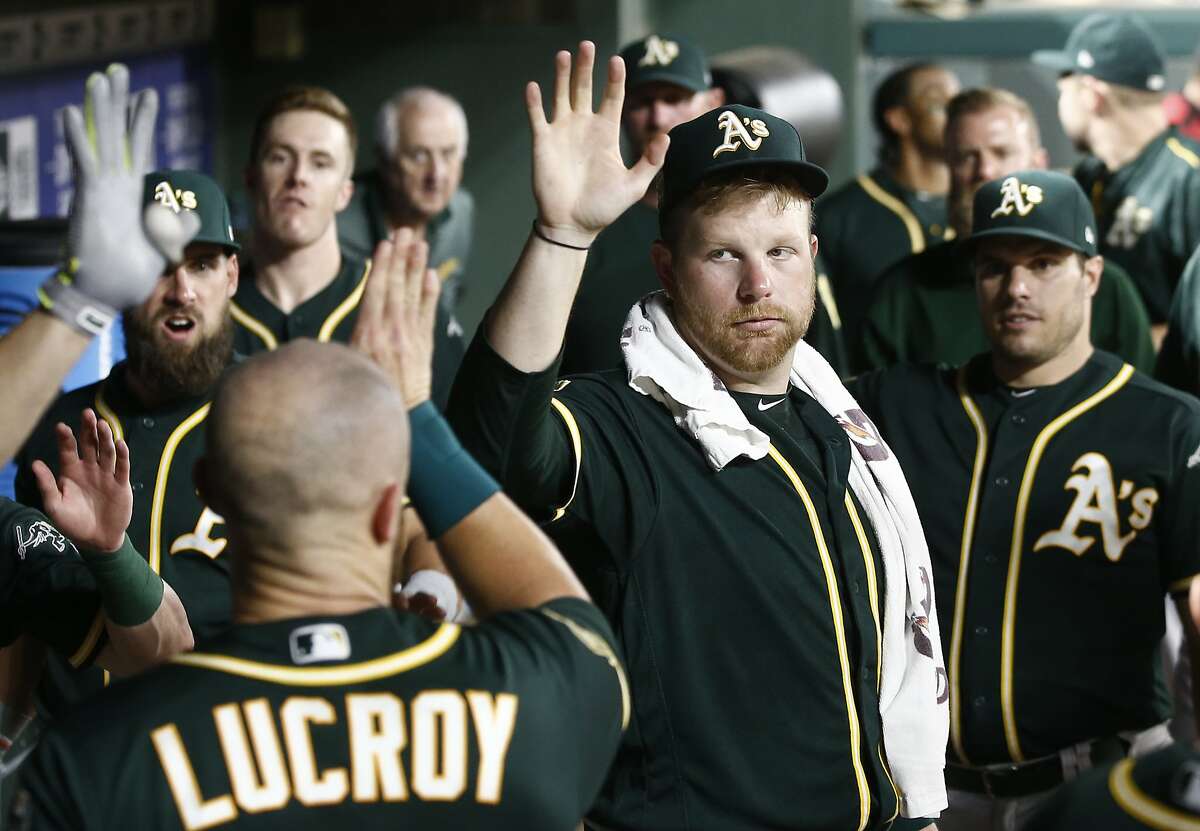 Oakland Athletics starting pitcher Brett Anderson, center, congratulates Jonathan Lucroy after he scored against the Texas Rangers during the seventh inning of a baseball game Monday, July 23, 2018, in Arlington, Texas. (AP Photo/Mike Stone)