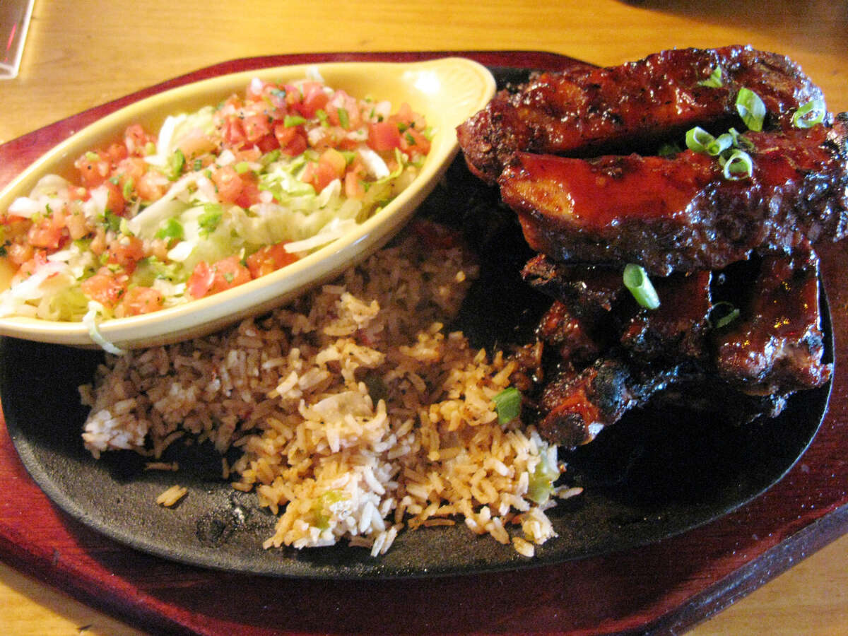 Spicy Chipotle Smoked Ribs at Lupe Tortilla are served with rice and a Mexican salad.