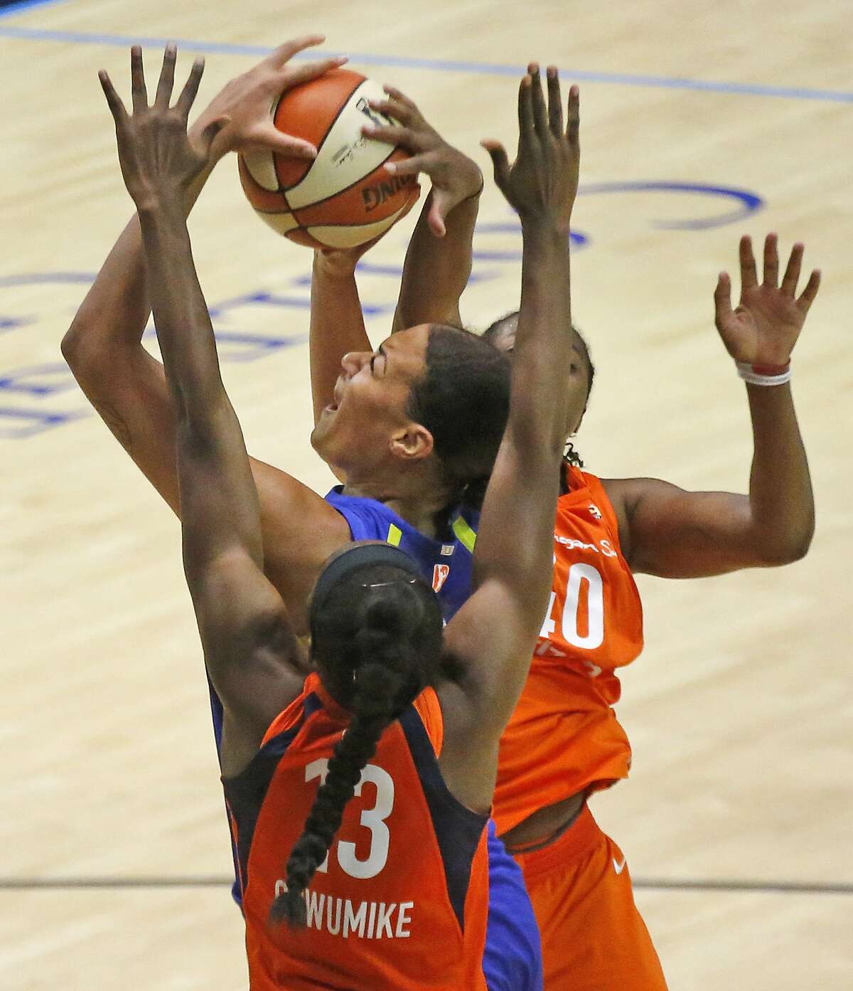 Dallas Wings center Liz Cambage (8) shoots between Connecticut's Chiney Ogwumike (13) and Courtney Williams (10) in the fourth quarter of a WNBA basketball game in Arlington, Texas, Sunday, July 22, 2018. (Louis DeLuca/The Dallas Morning News via AP)