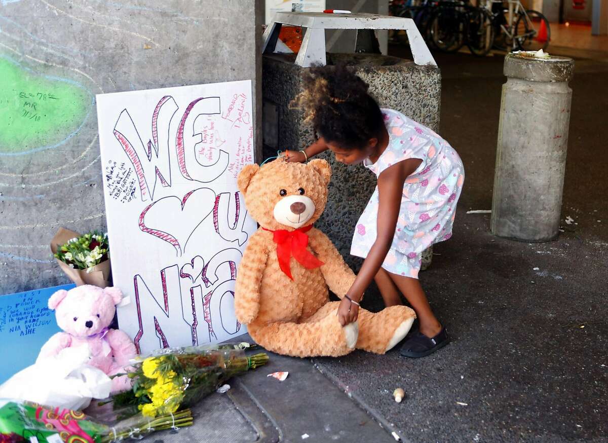 Sterling Moss, of Berkeley, leaves a teddy bear at the MacArthur BART station on July 24, 2018 for Nia Wilson, who was stabbed there on Sunday.