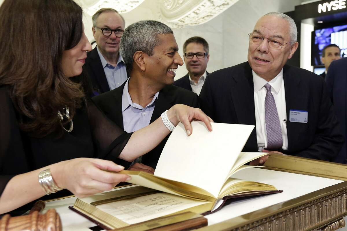 Bloom Energy Founder, President and CEO K.R. Sridhar, center accompanied by board member Colin Powell, right, prepares to sign the New York Stock Exchange guest book with NYSE President Stacey Cunningham before their IPO, Wednesday, July 25, 2018. (AP Photo/Richard Drew)