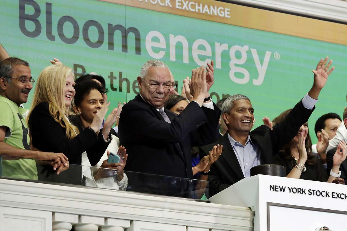 Bloom Energy Founder, President and CEO K.R. Sridhar, right, is applauded by board member Colin Powell, center, and company officials as he rings the New York Stock Exchange opening bell, Wednesday, July 25, 2018, to mark their IPO. (AP Photo/Richard Drew)