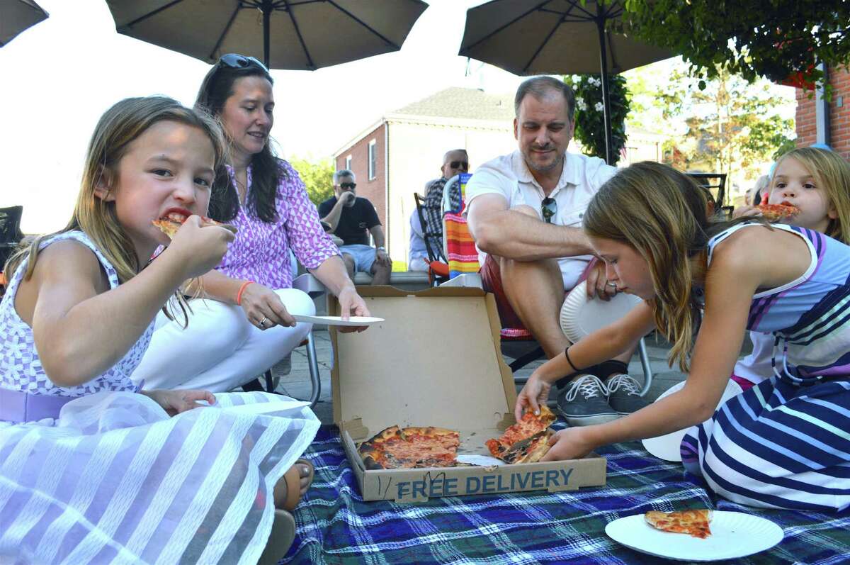 The Heins family of Darien shares a pizza party at the Darien Summer Nights concert series at Grove Street Plaza, Friday, July 20, 2018, in Darien, Conn.