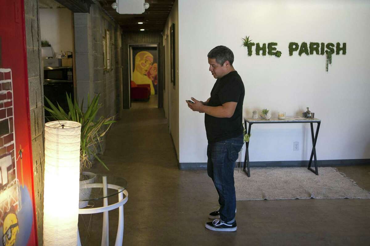 John Alexander Silvia checks his phone as he waits on a client at The Parish. In addition to the studios, there are several communal spaces where artists can relax, drink coffee, chat and bounce ideas off one another.